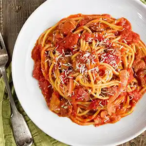 Teller mit Nudeln, Speck, Pecorino und Tomaten.