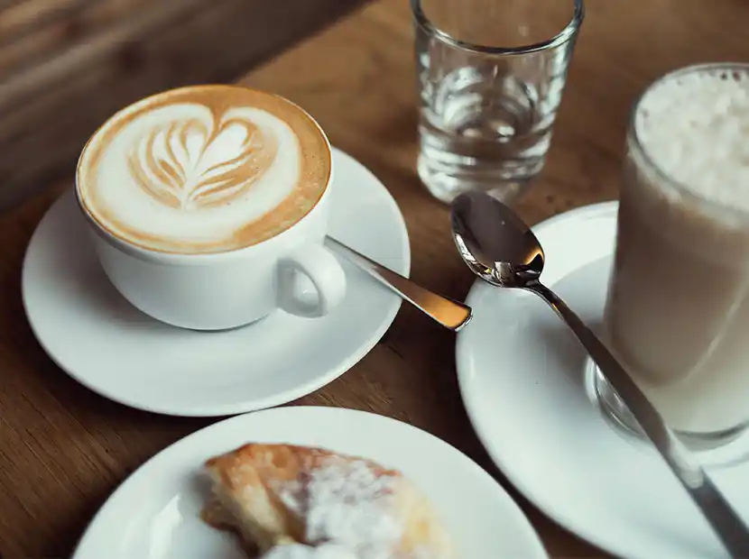 Frühstückstisch mit Cappuccino und Croissant.