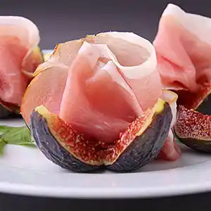 Schälchen mit San Daniele Schinken auf Feigen und Rucolasalat.