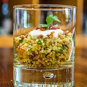 Couscous mit Gemüse an Sauerrahm mit Minzgarnitur im Glas.