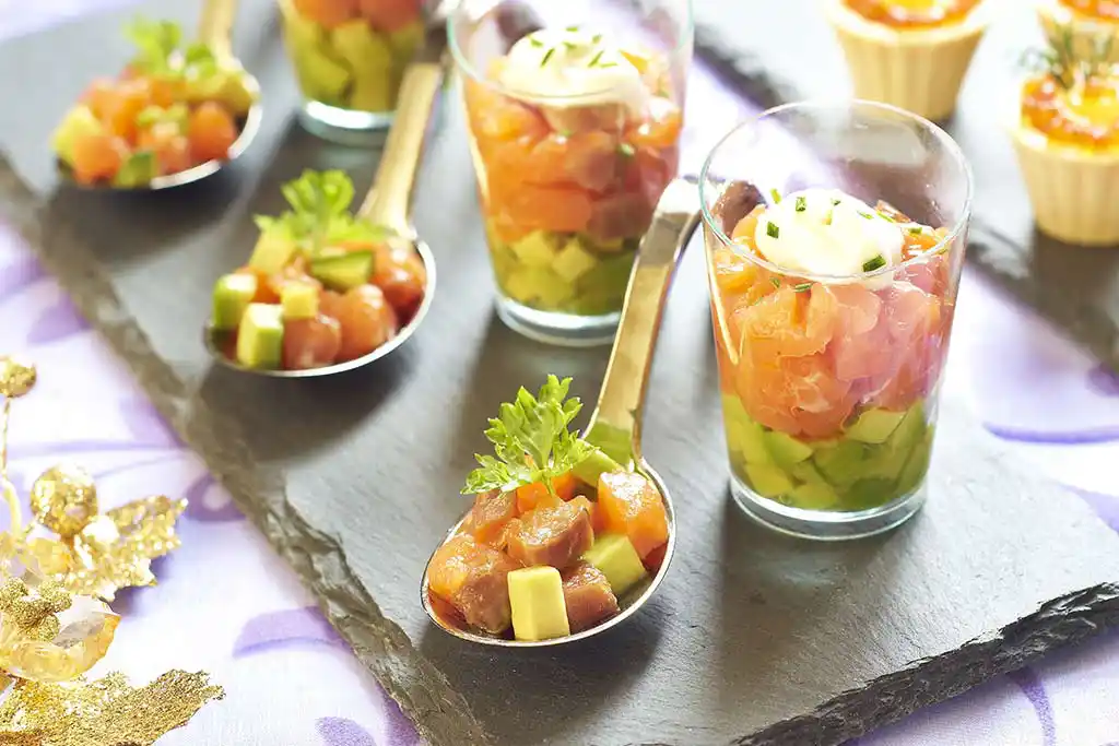 Auf Löffel und im Glas angerichtet Thunfisch-, Matjes- und Lachswürfel mit Gurken, Dill und Meerretich-Sahne.