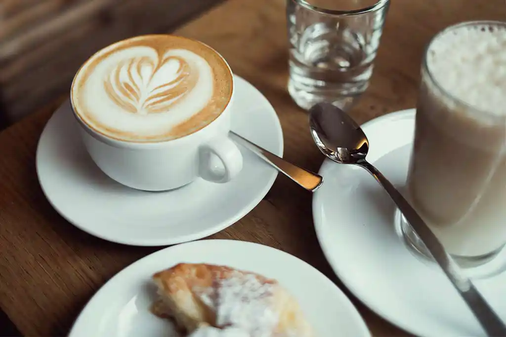 Frühstückstisch mit Cappuccino und Croissant.