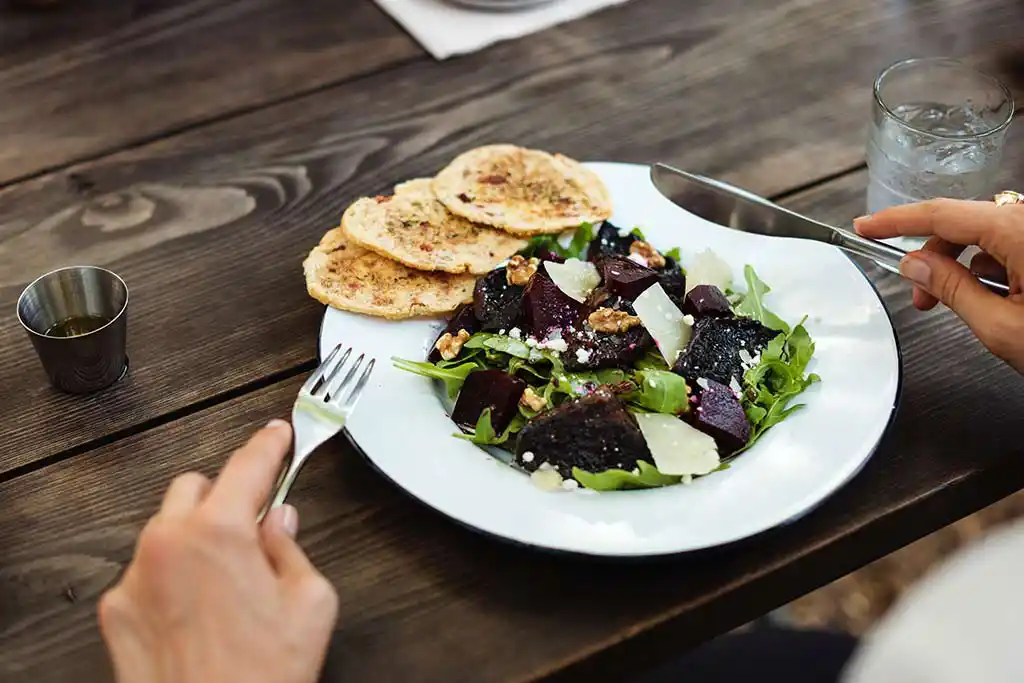 Teller mit Feldsalat, roter Beete, Parmesan und geröstetem und gewürzten Weißbrottalern.