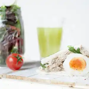 Holzbrett mit Thunfisch-Tramezzini, Ei, gemischter Salat und Zitronen-Ingwerlimonade.