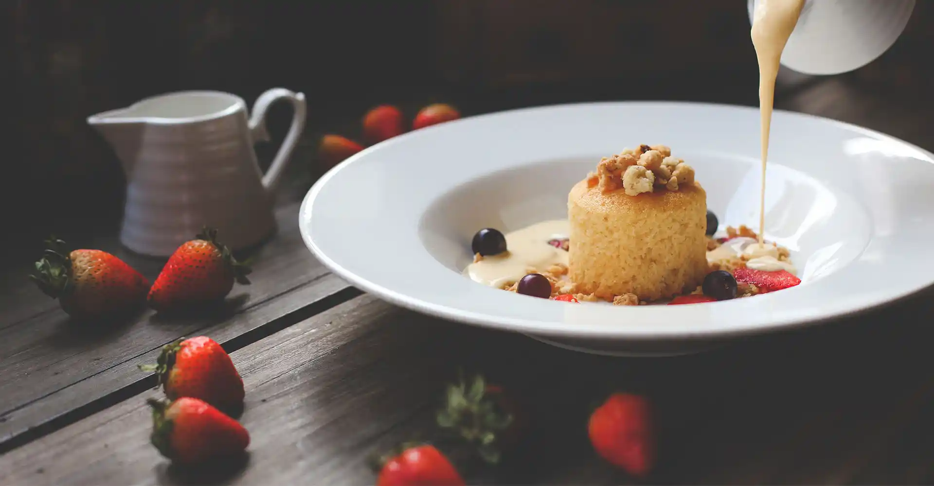 Teller mit Haselnuss-Soufflé und Beeren an warmer Vanillesauce.