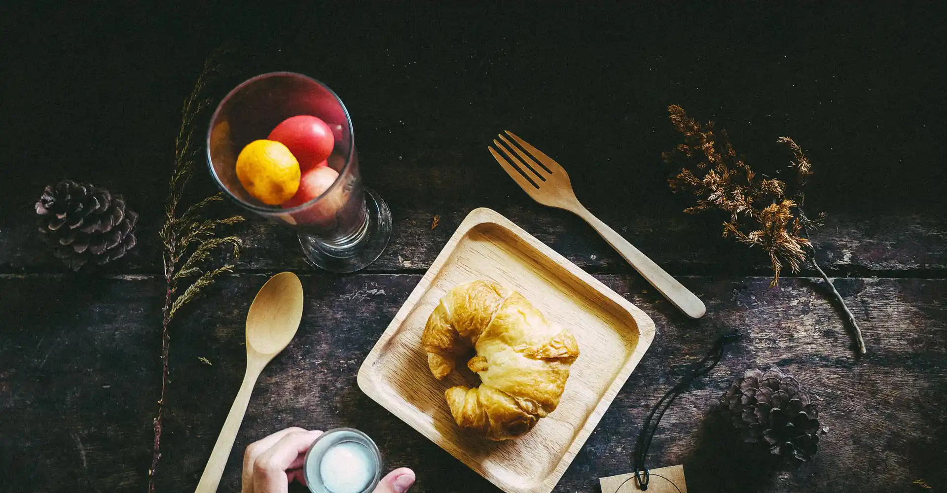 Holztisch mit Obst und Teller mit Croissant.
