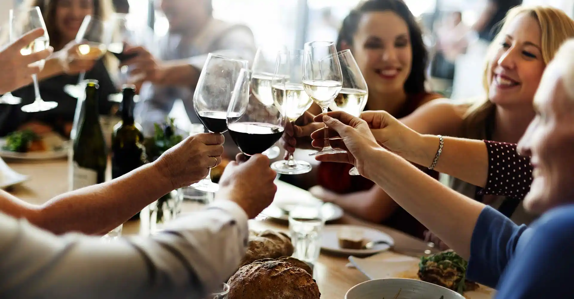Freunde am Tisch stoßen mit Wein an.