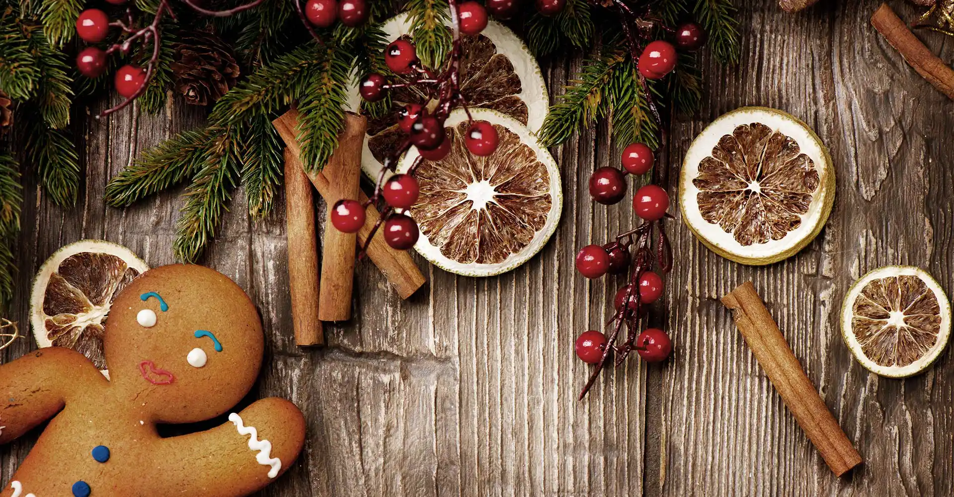 Lebkuchen, Zimtstangen und getrocknete Orangen auf einem Holztisch.