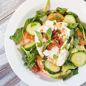 Salatteller mit Spinat, Gurken, Tomaten, Crème fraîche und Basilikum.
