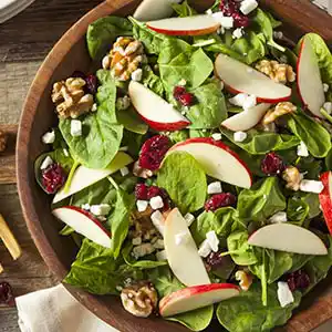 Salatteller mit Spinat, Schafskäse, Cranberries, Apfel und Nüssen.