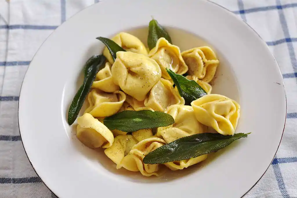 Teller mit Teigtaschen gefüllt mit Salbei und Buttersauce.