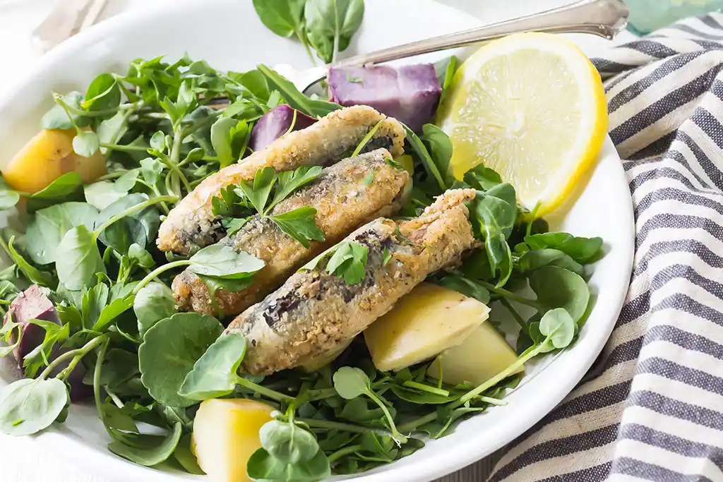 Gebratene Sardellen mit Parmesan an Blattsalat.