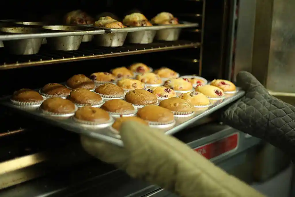 Fertige Muffins werden aus dem Ofen geholt