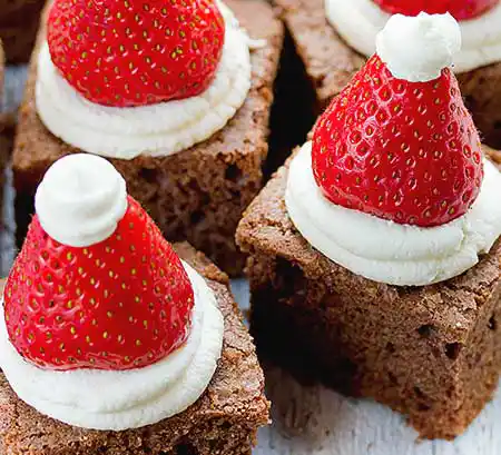 Brownies mit Weihnachtsmannmütze aus Erdbeeren und Sahne.