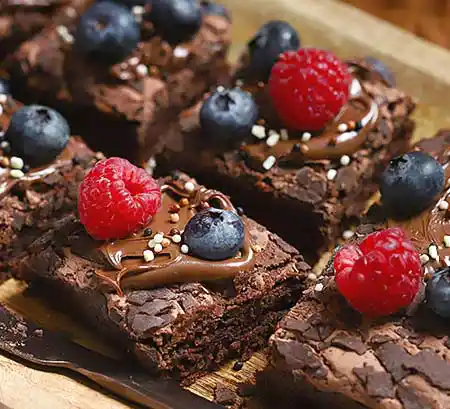 Tablett mit Brownie mit Topping aus Beeren und dunkler Schokolade.