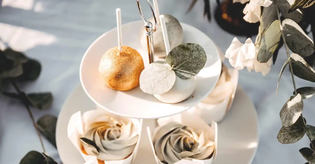 Dekorierter Tisch Etagerer und 2 Cakepops in Gold und Weiß.