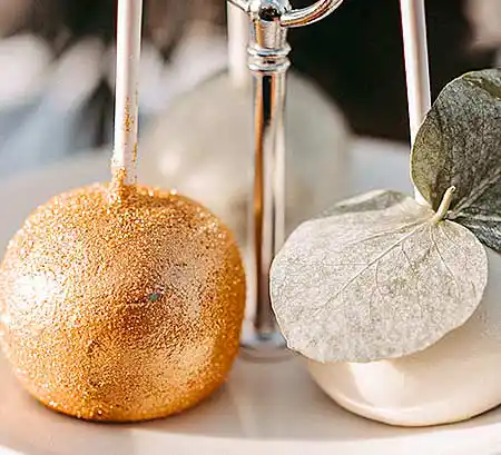 Goldene und weiße Cake-Pops auf einem Silbertablett.
