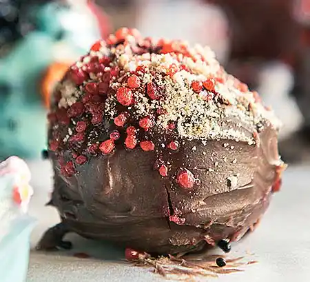Cake-Pop mit Mantel aus Vollmilch-Schoko-Creme. Dekoration Früchtesprenkel und Nusspulver.