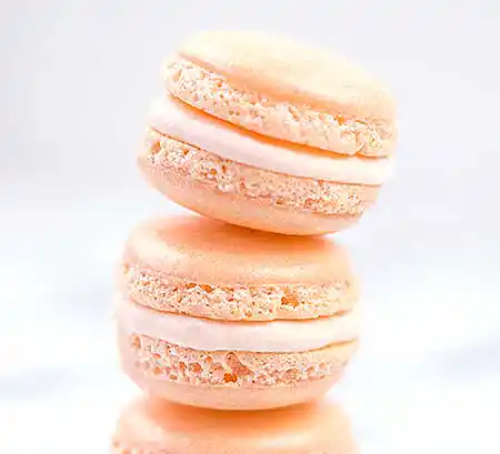 2 pfirsichfarbene Macarons übereinander.