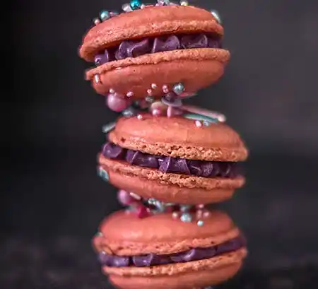 3er Stapel aus pinkfarbenen Macarons mit Zuckerperlen.