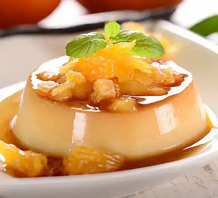 Teller mit frisch gestürzte Panna Cotta mit köstlichem Karamell mit Orangen-Filets und Minze.