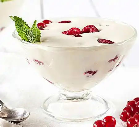 Glasschale mit Zabaione mit Himbeeren und Minzgarnitur.
