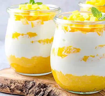 Gläser mit Sahne-Mascarpone-Créme mit frisch pürierter Mango und gestückelter Mango.