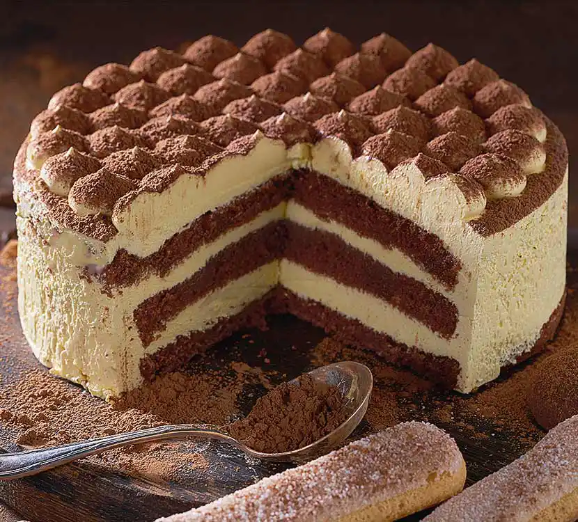 Holzbrett mit angeschnittener italienischer Torte, Kakao und Biskuit.