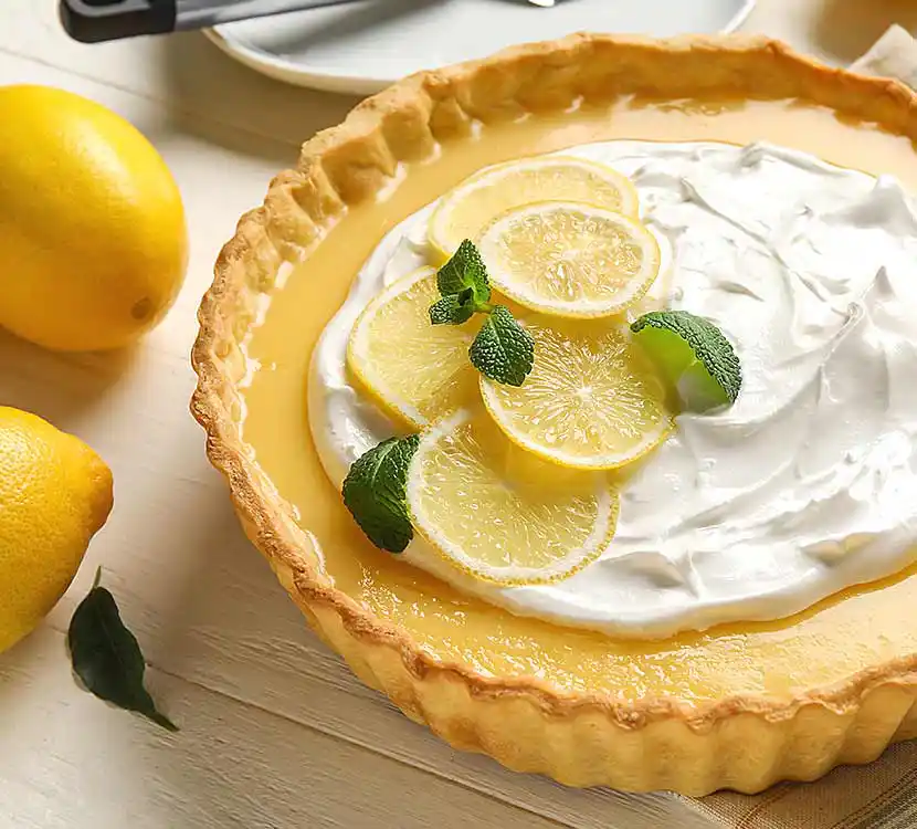 Zitronenkuchen auf Tisch mit Zitronen.