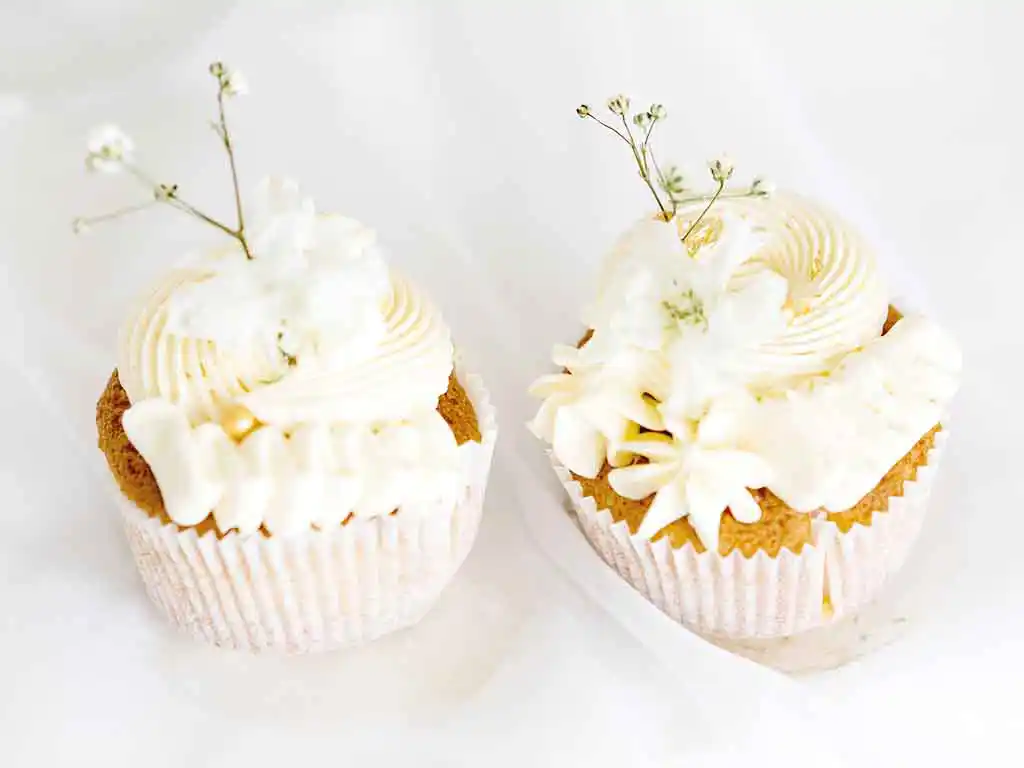 2 weiße Cupcakes mit Blumendekor.