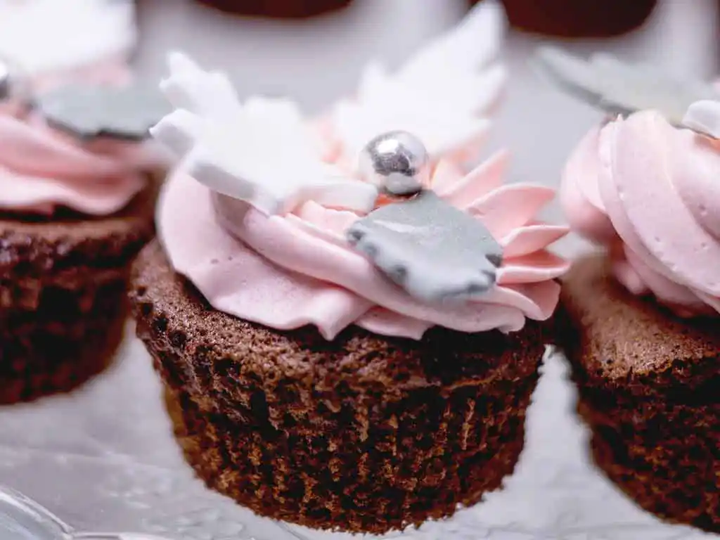Cupcake mit Topping aus und rosa Blätter und Fondant.