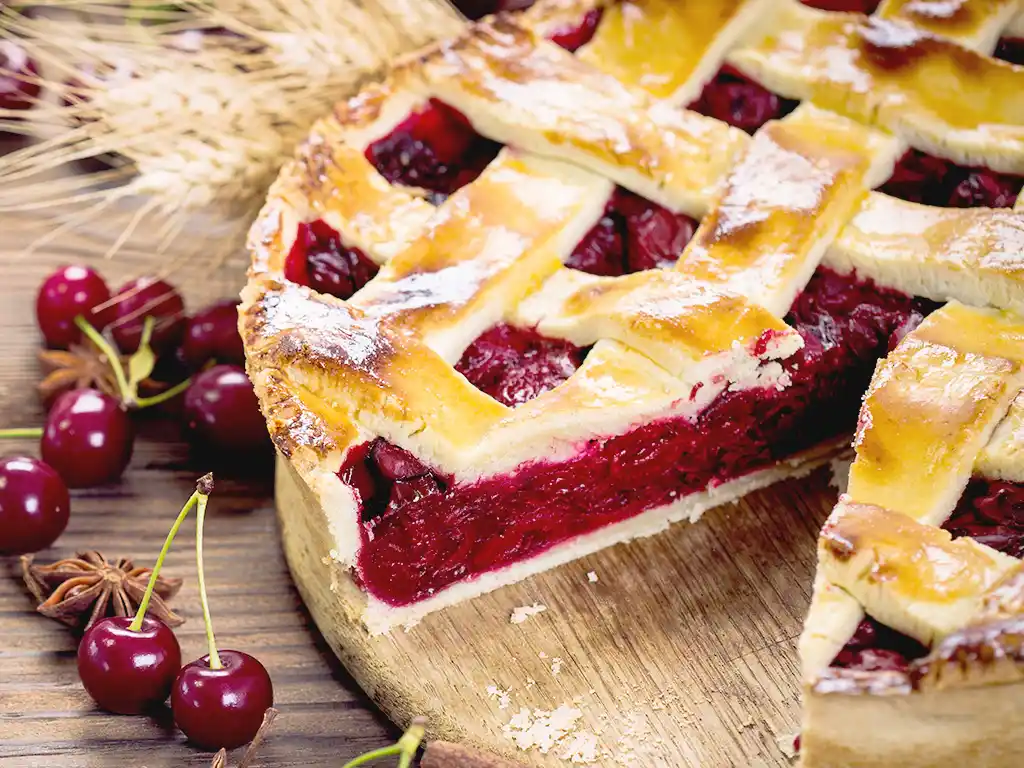 Holztablett mit Gitter-Zimt-Nusskuchen mit Kirschfüllung.