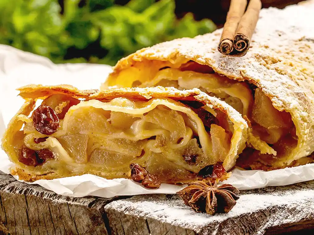 Holzbrett mit Apfel-Strudel und Zimtstange