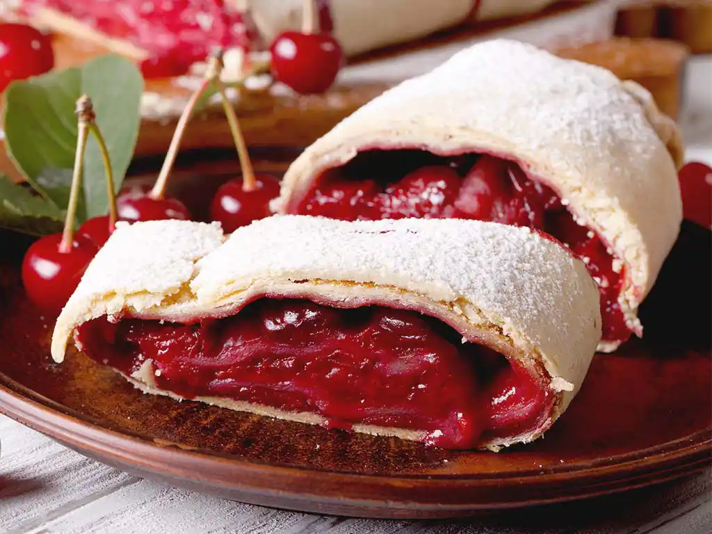 Teller mit Kirsch-Strudel und Kirschen.