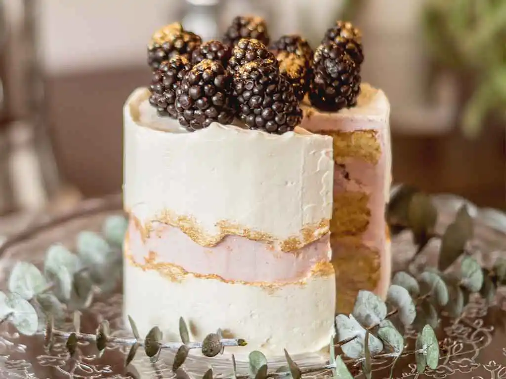 Tablett mit angeschnittener Torte und obendrauf Brombeeren.