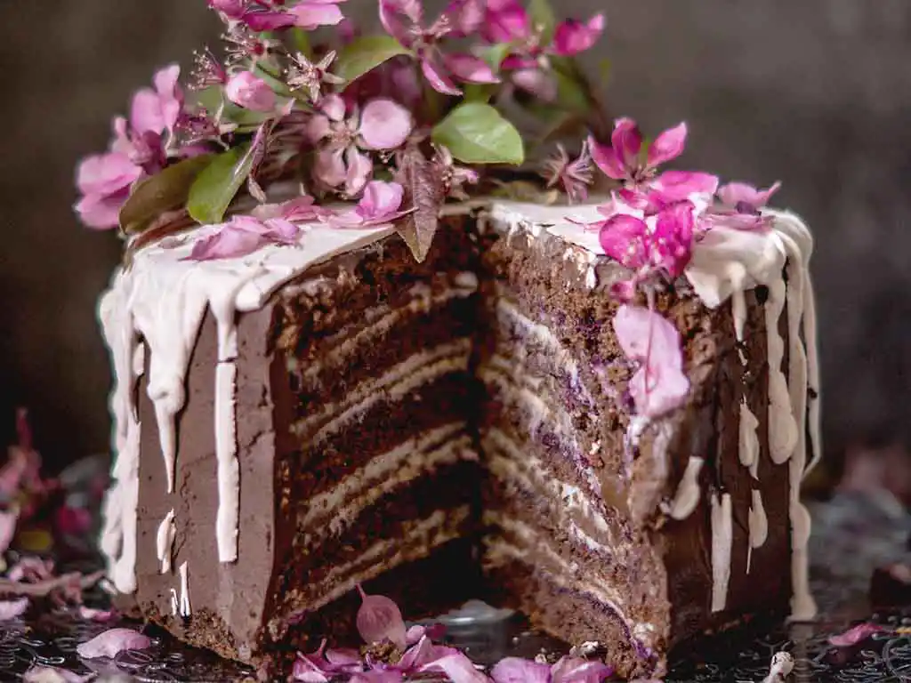 Angeschnittene Schokotorte mit roten Blumen.