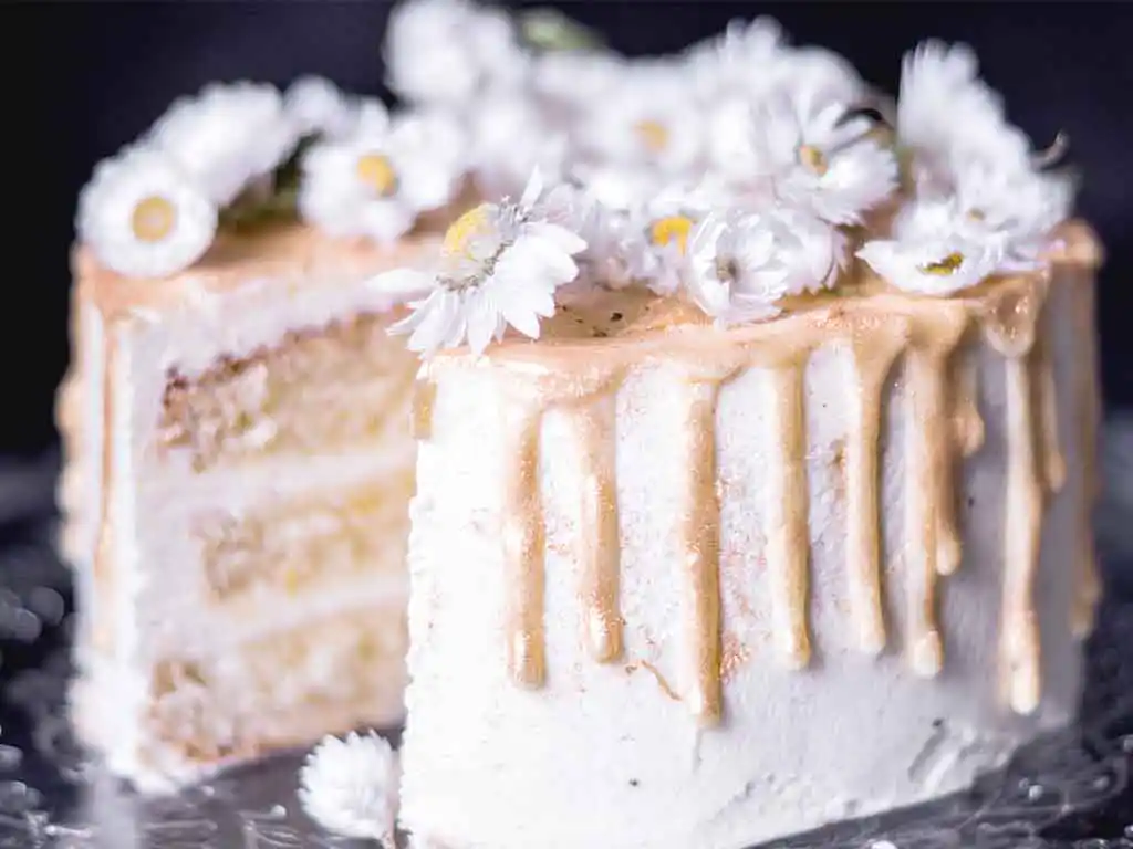 Angeschnittene kleine weiße Torte mit Gänseblümchen.