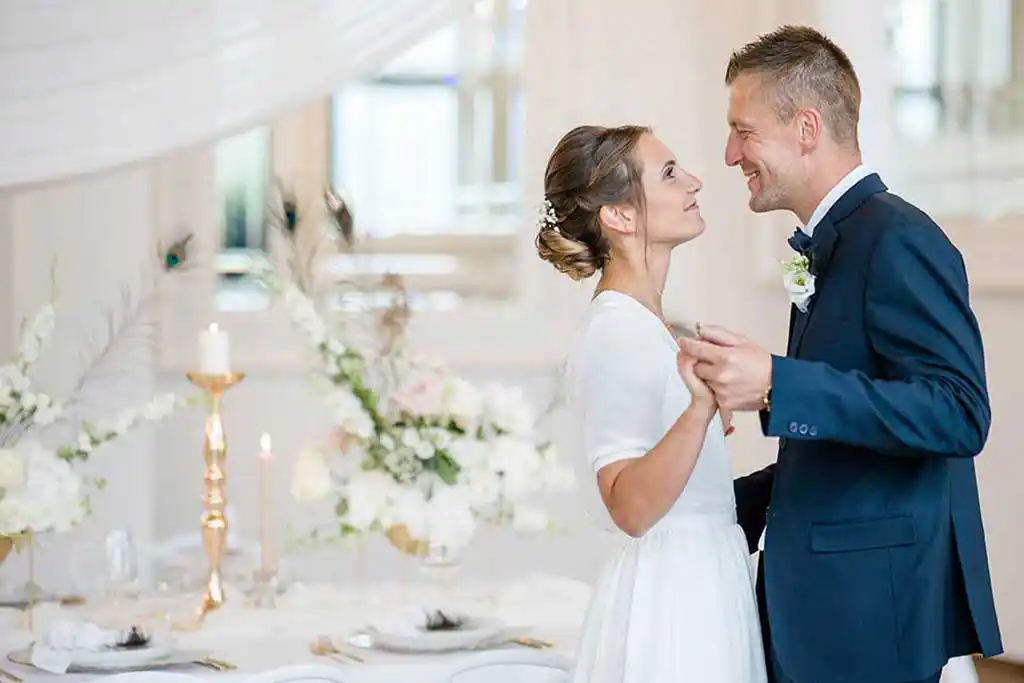 Brautpaar sieht sich an vor Hochzeitstisch.
